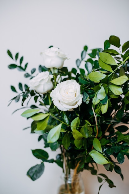 Composição floral no interior. Monte com rosas brancas e folhas verdes.