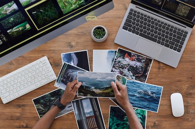 Composição mínima de fundo de mãos masculinas segurando fotografias impressas sobre uma mesa de madeira texturizada, conceito de escritório de fotógrafos, espaço de cópia