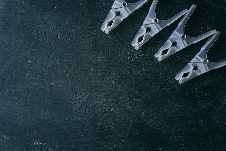 Foto composição minimalista de pinças de plástico translúcidas dispostas diagonalmente em um fundo de textura escura conceito doméstico com espaço de cópia