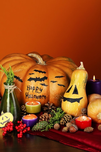 Composição para o Halloween com abóboras e velas em fundo laranja