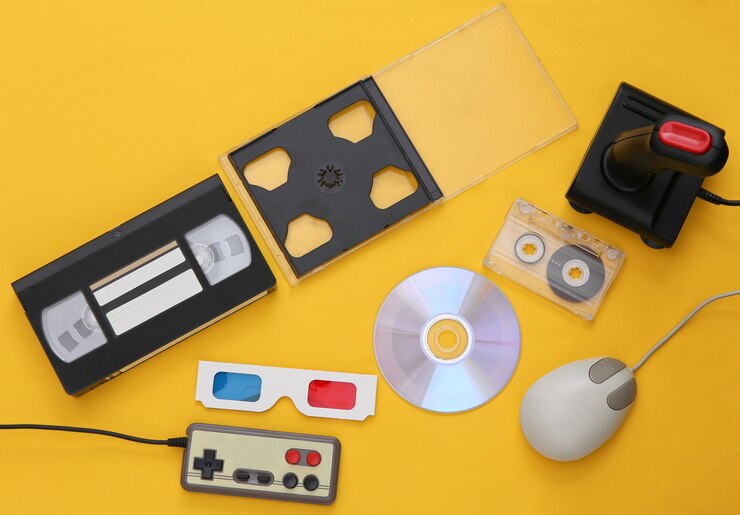 Foto composição plana de atributos dos anos 80. mouse para pc, gamepads, fitas de áudio e vídeo, cd, óculos 3d. eletrônica retro, gadgets e dispositivos. entretenimento e jogos. fundo amarelo. vista do topo