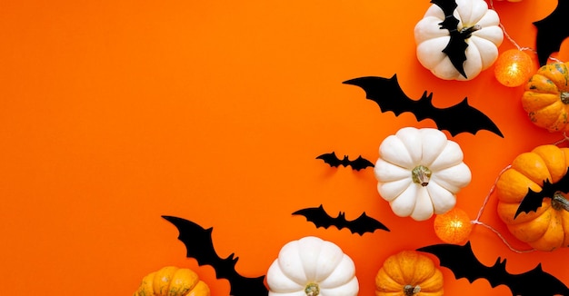 Composição plana de halloween de morcegos de papel preto e abóboras em fundo laranja conceito de halloween