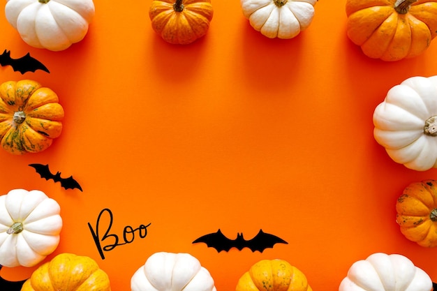 Composição plana de Halloween de morcegos de papel preto e abóboras em fundo laranja conceito de Halloween