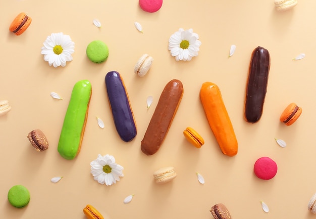 Composição plana de macaroons franceses coloridos, éclairs, flores brancas e pétalas