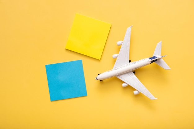 Composição plana de viagem no avião de fundo amarelo com papéis de nota em branco conceito de preparação de viagem