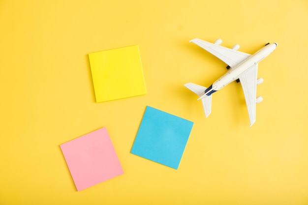 Composição plana de viagem no avião de fundo amarelo com papéis de nota em branco conceito de preparação de viagem