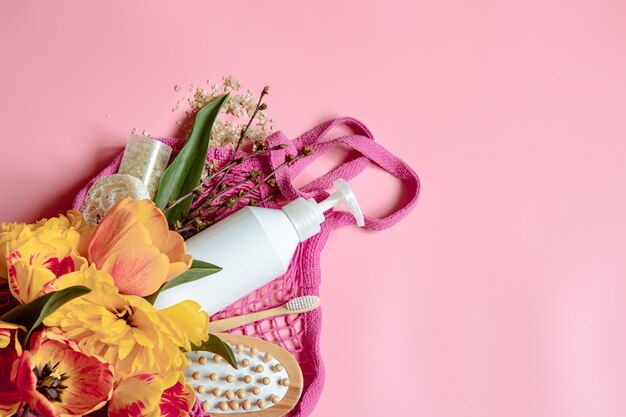 Composição plana lay spa com flores e acessórios de banho em uma bolsa de barbante.