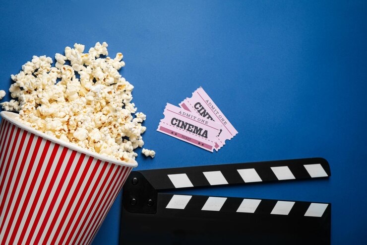 Foto composição plana leiga com deliciosas pipocas e itens de cinema em fundo azul