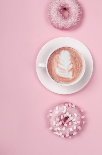 Composição plana leiga com dois donuts e uma xícara de café em rosa