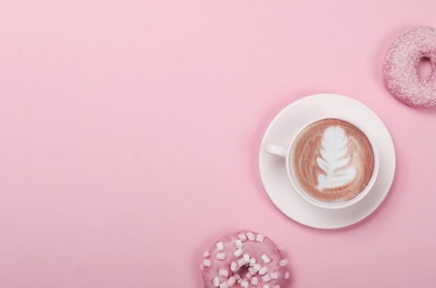 Composição plana leiga com donuts e xícara de café no fundo rosa