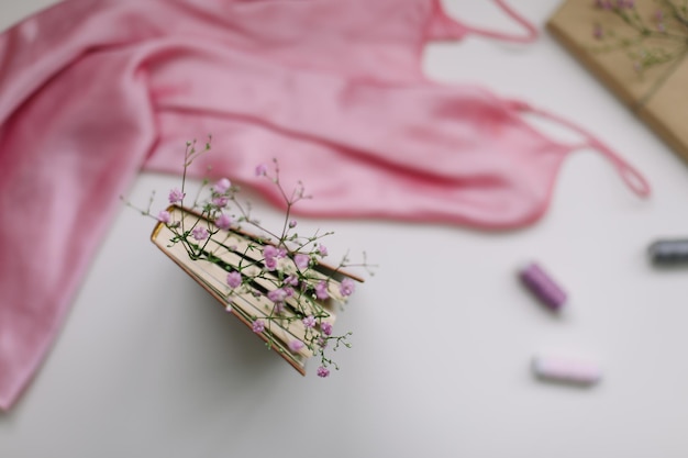 Composição plana leiga com elegantes flores de livro de vestido rosa na vista superior de fundo branco