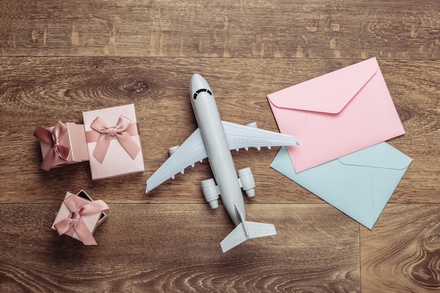 Composição plana leiga com figura de avião, caixas de presente e envelopes de cartas no chão.