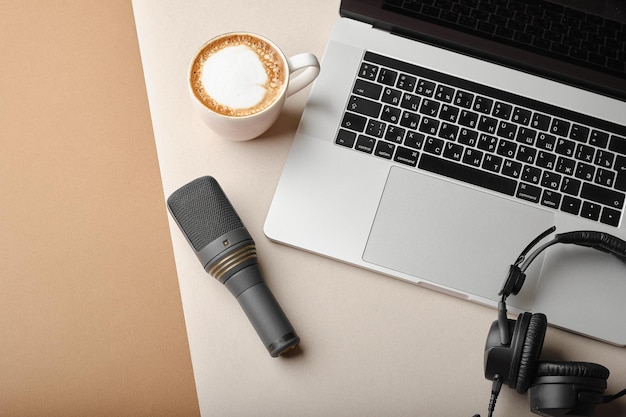 Composição plana leiga com microfone para podcasts e fones de ouvido de estúdio preto em fundo marrom com café e laptop aprendendo conceito de educação on-line