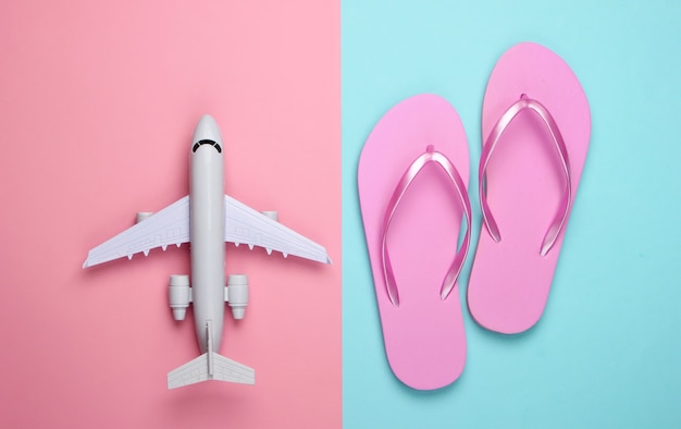 Composição plana leiga de viagens. Estatueta de avião, chinelos em pastel azul rosa.