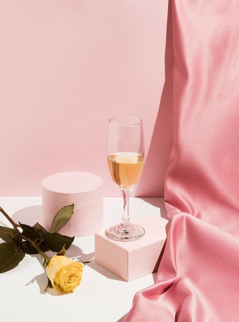 Composição romântica do Dia dos Namorados rosa pastel com cortina de cetim de vidro de vinho e flor de rosa amarela