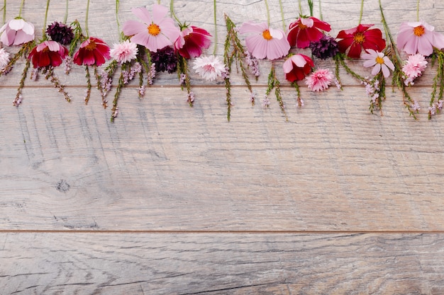 Composição rosa flores roxas em placas de madeira. Flores silvestres no fundo da mesa de madeira artesanal. Pano de fundo com espaço de cópia, vista plana, vista superior. Conceito de dia do casamento da mãe, dia dos namorados, mulheres.