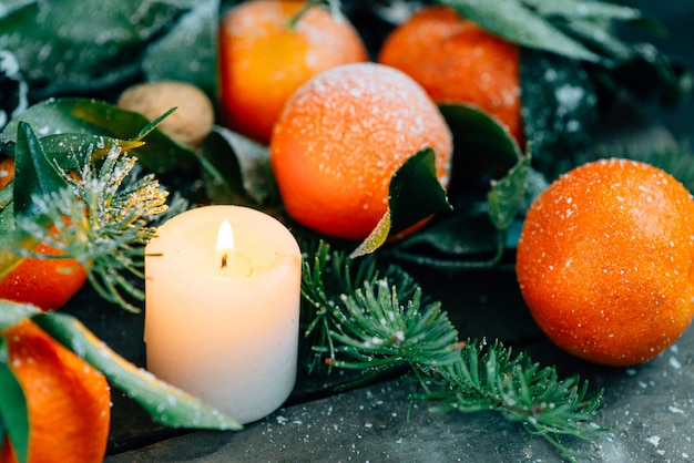 Composição tonificada do Natal da imagem com as tangerinas, os cones do pinho, as nozes e as velas no fundo de madeira.