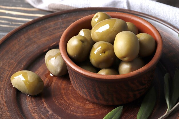 Composición de aceitunas verdes; aceite de oliva; adobo sobre un fondo de madera cerrar