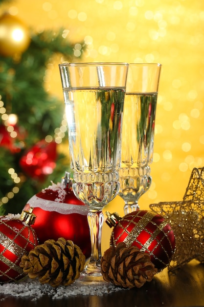 Composición con adornos navideños y dos copas de champán, sobre fondo brillante