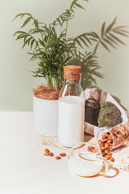 Composición alimentaria con taza de leche de almendra botella de leche vegetal almendra brócoli y planta de la casa