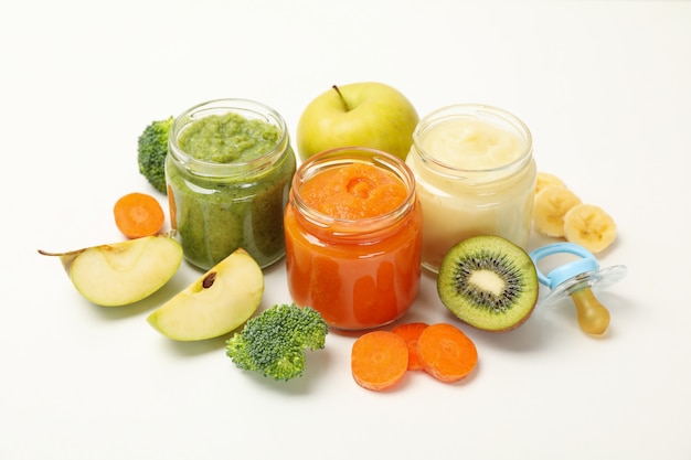 Composición con los alimentos para niños en el fondo blanco. Puré de verduras