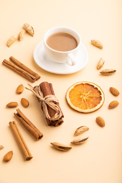 Composición con almendras canela y taza de café sobre fondo naranja pastel vista lateral de cerca