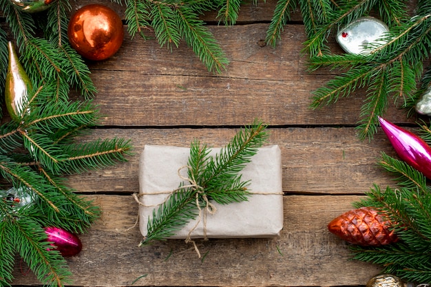Composición de año nuevo de adornos para árboles de Navidad y ramas de abeto. Regalo envuelto en papel artesanal de una ramita de abeto.