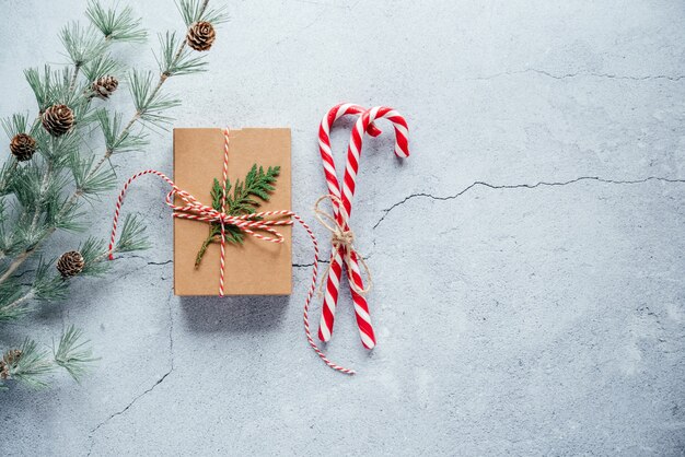 Composición de año nuevo con caja de regalo de Navidad, piñas y ramas de tuya