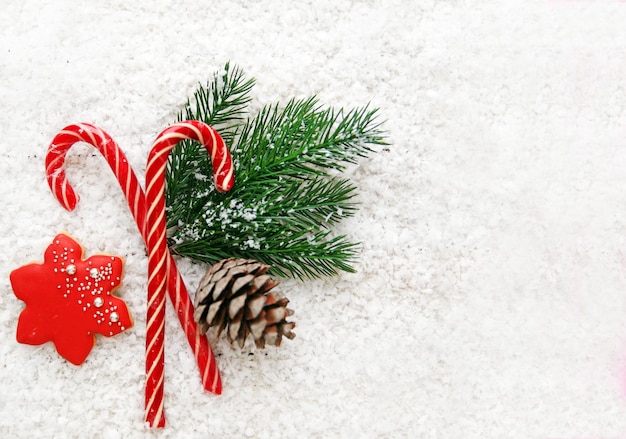 Foto composición de año nuevo dulces de navidad pan de jengibre ramas de pino y una protuberancia en un fondo blanco nevado vista superior plana