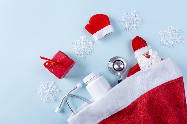 Composición de año nuevo médico laico plano con estetoscopio, pastillas, caja de regalo y decoración navideña
