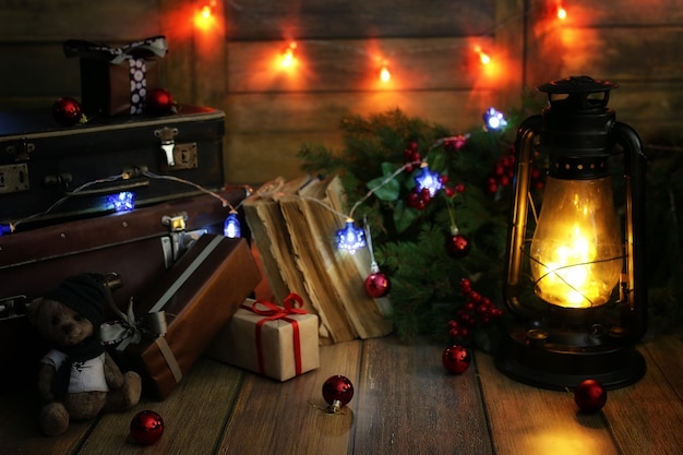 Composición de año nuevo de ramas de árboles de Navidad decoradas con bolas Lámpara vintage con velas encendidas y cajas llenas de regalos