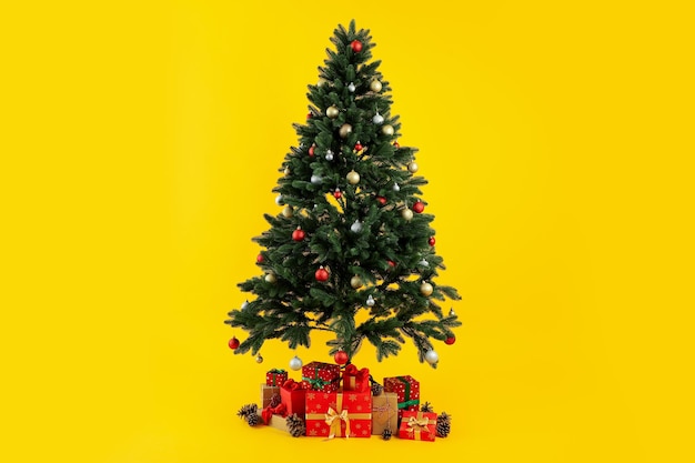 Composición con árbol de Navidad y regalos sobre fondo amarillo