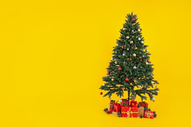 Composición con árbol de Navidad y regalos sobre fondo amarillo