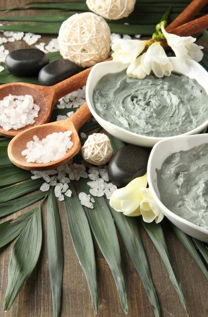 Composición con arcilla cosmética para tratamientos de spa sobre fondo de hoja de palma