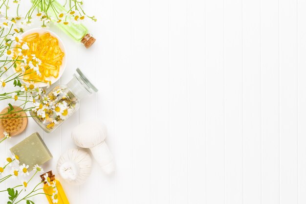 Composición de aromaterapia con cosmética natural y flores de manzanilla sobre fondo claro.