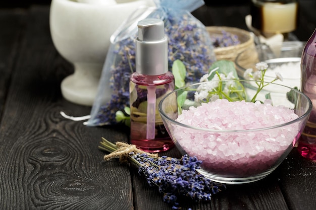 Composición aromática de lavanda, hierbas, cosméticos y sal sobre una mesa oscura