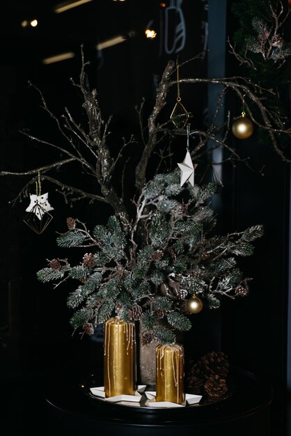 Foto composición artística de ramas de coníferas con conos decorados con nieve artificial velas doradas