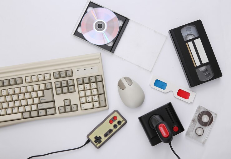 Foto composición de atributos plana de los años 80. teclado de pc, mouse, gamepads, cintas de audio y video, cd, lentes 3d. electrónica retro, gadgets y dispositivos. entretenimiento y juegos. fondo blanco. vista superior