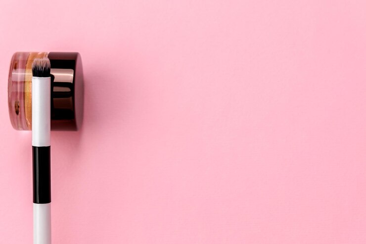 Foto composición de belleza de un solo pincel cosmético y sombra de ojos de crema sobre un fondo rosa con espacio