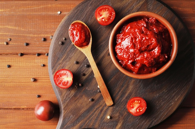 Foto composición de un bol con salsa de tomate e ingredientes para cocinar sobre un fondo de madera vista superior
