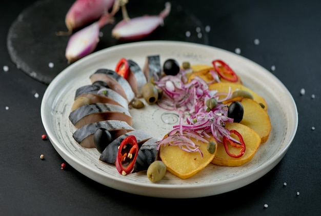 Composición de caballa salada con guarnición de patatas cebollas servidas en una tabla de madera