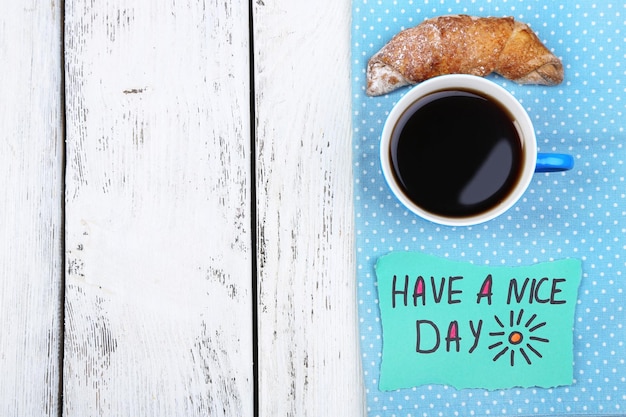 Foto composición de café croissant recién hecho y tarjeta de papel en servilleta sobre fondo de madera