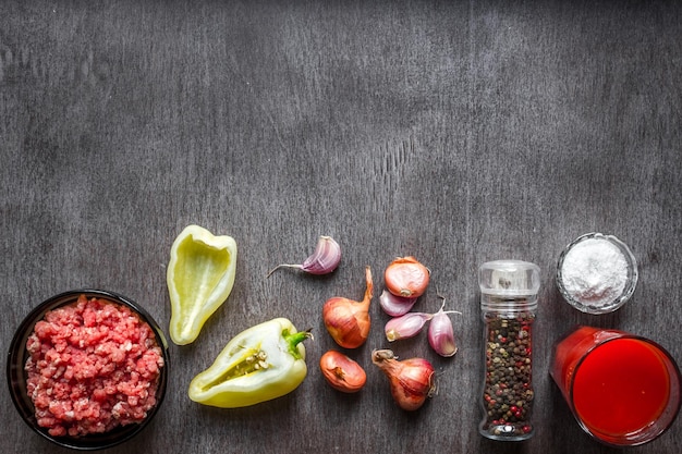 Composición de carne cruda con verduras y especias sobre fondo de madera