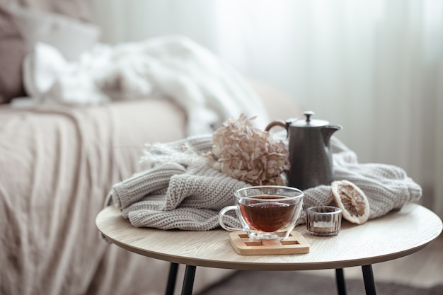 Composición de la casa de otoño con una taza de té, una tetera y un elemento de punto.