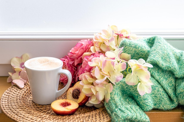 Composición casera con una taza de flores de café y un elemento de punto.