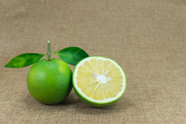 Composición de cítricos con hojas sobre fondo de tela marrón