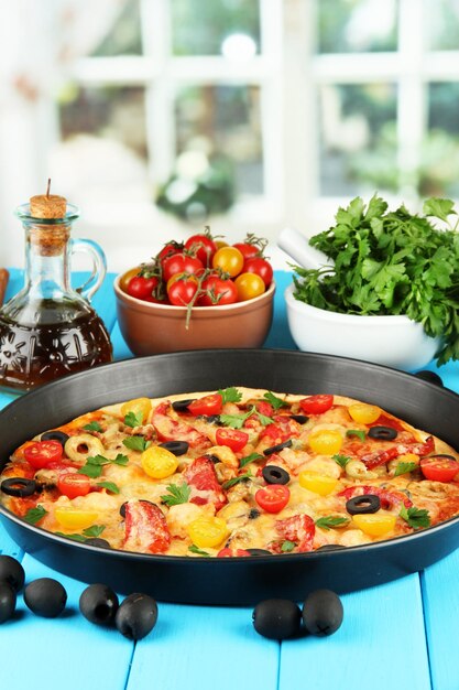 Composición colorida de deliciosas verduras y especias de pizza en un primer plano de fondo de madera azul