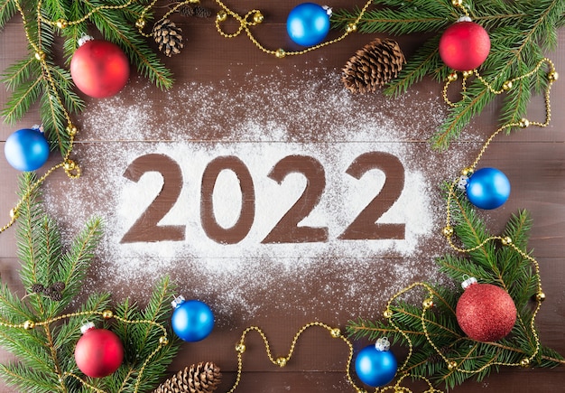 Foto composición de conos de bolas de ramas de abeto con la inscripción 2022 navidad y año nuevo