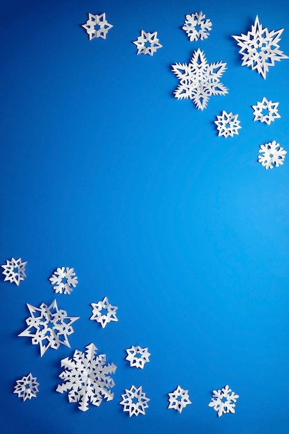 Composición con copos de nieve de papel en azul