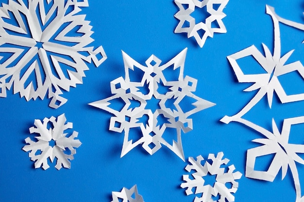 Composición con copos de nieve de papel sobre papel azul